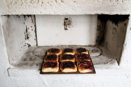 Delicious pies with berry filling lie on a wooden cutting board, on a Russian stove. Traditional cuisine.の写真素材