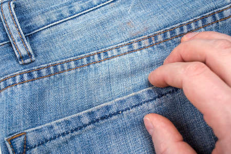 Hand something puts or takes out the jeans pocket. Close-up.の写真素材