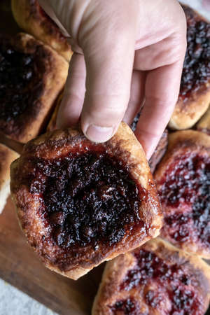 Hand holds a delicious, appetizing homemade pie with berry filling, cooked in a Russian oven. Hearty, hot snack. Traditional cuisine.の写真素材