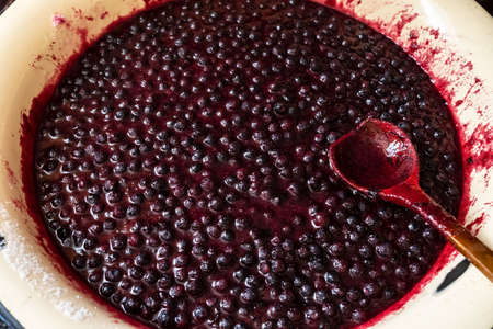 Jam made from blueberries in a metal basin with a wooden spoon. Traditional preparation of a sweet dessert in the countryside.の写真素材
