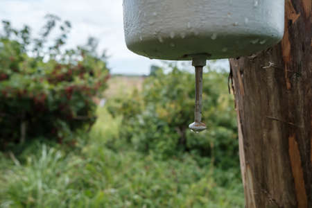 Old, metal washbasin attached to a wooden post, in a courtyard, in the countryside. Rural traditions and hygiene outdoors.の写真素材