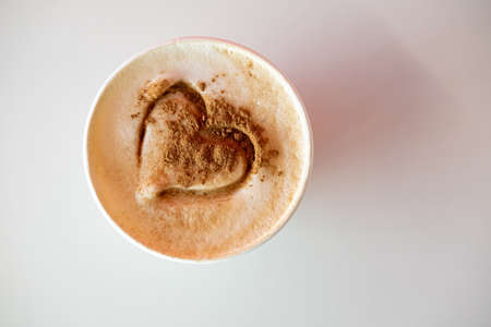 Cappuccino with cinnamon and a drawn heart on lush foam. Invigorating, aromatic morning drink. View from above.の写真素材