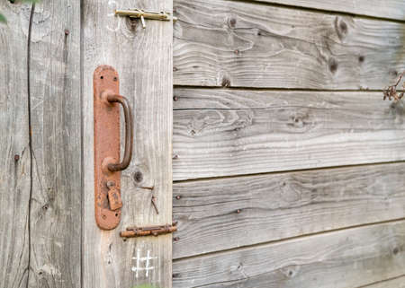 Rusty doorknob and two latches on a wooden barn or toilet door, in the countryside. Copy space.の写真素材