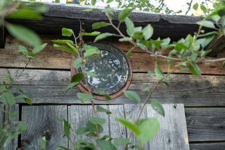 Round window under the roof of an old wooden shed or toilet, in a village courtyard.の写真素材