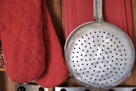 Aluminum colander hangs on the wall of a country house. Kitchen utensils, close-up.の写真素材