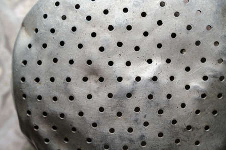 Crumpled old aluminum colander with holes. Close-up.の写真素材
