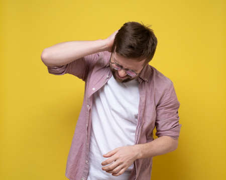 Man experiences severe pain in the back of the head or neck, he holds on to the inflamed area with hand and suffers.の写真素材