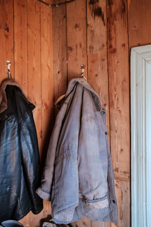 Warm jackets for work in the garden hang on a wooden wall in a country house.の写真素材