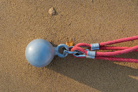 Metal fastening and a red rope, on the playground, against the background of a soft surface, outdoors.の写真素材