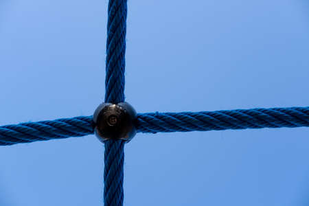 Ropes fastened together on the playground, in the open air, against the background of a blue sky. Part of the play equipment. Abstract background.の写真素材