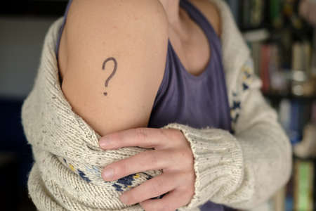 Female shoulder with a drawn question mark. Concept of uncertainty, whether or not to vaccinateの写真素材