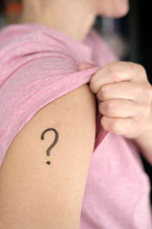 Shoulder with a drawn question mark. Concept of uncertainty, whether or not to vaccinate against  and which vaccine to choose.の写真素材