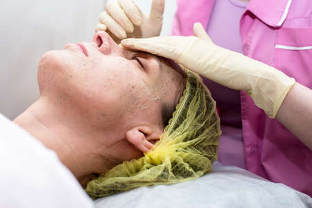 Hands of the beautician cleanse the skin of the woman face with massaging movements using a scrub.の写真素材