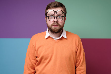 Strange man in a stupor, he put on two pairs of glasses and looks into the camera with big eyes. Colorful background.の写真素材