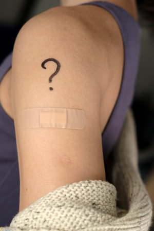 Female shoulder with drawn question mark and bandage after  vaccination. Vaccine selection concept.の写真素材