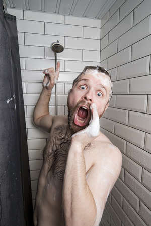 Worried man in soapy foam asks for help, the shower runs out of water or something breaks, he shouts and points to the watering can.の写真素材