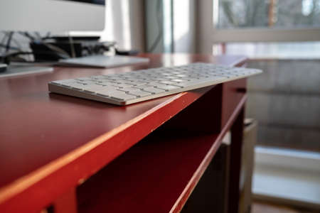 Keyboard is left carelessly on the edge of the desktop and may fall over. Nonchalance attitude to gadgets.の写真素材