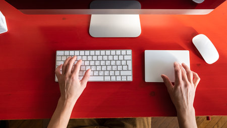 Female hands work with a keyboard and a touchpad, a mouse and a computer are nearby. Remote work. Contemporary workplace.の写真素材