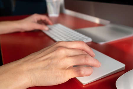 Female hands work with a keyboard and a touchpad, a computer is nearby. Remote work. Contemporary workplace and lifestyle.の写真素材