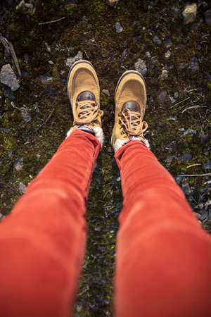 Female feet in yellow suede boots stand in moss with stones. Top view. Vertical photo.の写真素材