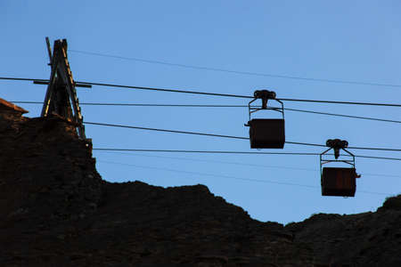 Silhouette of an old cable car and two trolleys for coal mining, at sunset, against a sky. Energy crisis concept.の写真素材