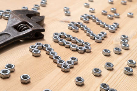 Number 2022 is lined with metal nuts on a wooden table next to a large, old wrench. Concept of preparing for the New Year.の写真素材