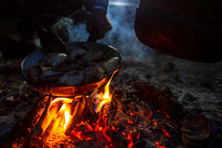 Chunks of freshly caught fish are fried in a pan over a campfire, over a fire, late at night, at a campground. Hobby and lifestyle.の写真素材
