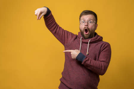 Shocked man showing fingers as if he is holding or picking up an invisible object and points at it with forefinger. Copy space.の写真素材