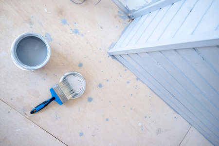 Brush is on the lid next to a metal can containing gray paint. Painting a wooden wall. Home renovation.の写真素材