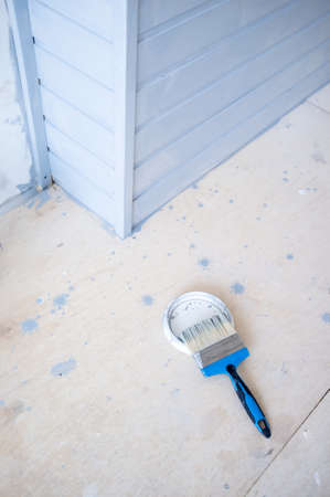 Brush in gray paint lies on a metal cover. Painting a wooden wall. Home renovation.の写真素材