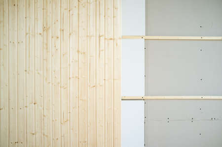Part of the wall is made of new wooden slats, the other is made of plasterboard. Work process. Home repairs. Copy space. Background.の写真素材