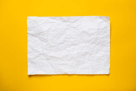 Frame from a crumpled, straightened sheet of white paper on a yellow background. Copy space. Top view.の写真素材