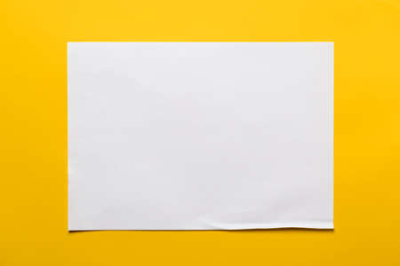 Frame of a sheet of white paper on a yellow background. Copy space. Top view.
