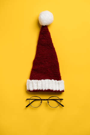 Santa Claus hat and the round glasses underneath it looks like a face on a yellow background. New Year sale of eye accessories.の写真素材