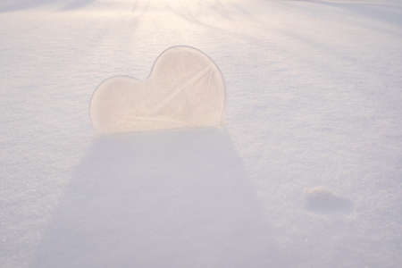 Heart is a symbol of love, made of ice, in the snow, in the rays of the setting sun. Valentines Day. Romantic concept. Copy space.の写真素材
