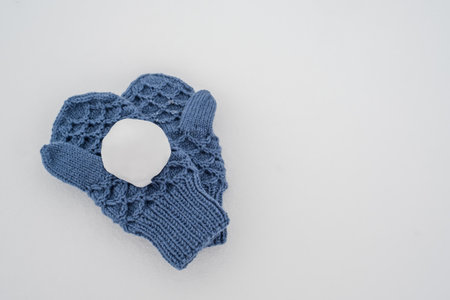 Snowball on blue knitted mittens, in the snow. Winter active games and fun. Copy space.の写真素材
