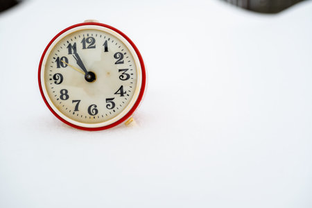 Old mechanical alarm clock in the snow, on a winter day. Copy space.の写真素材