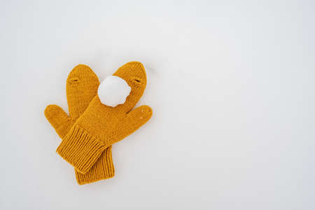 Snowball on yellow knitted mittens, in the snow. Winter active games and entertainment. Copy space.の写真素材