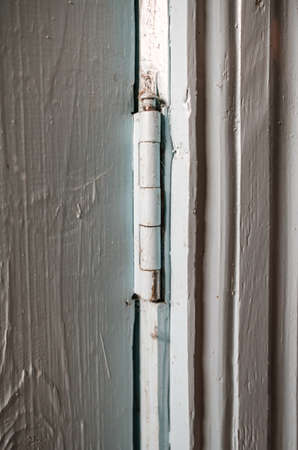 Metal hinge on a wooden painted door indoors, in a rural house. Country style.の写真素材