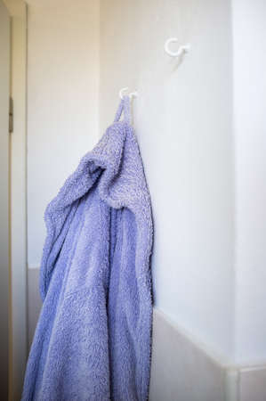 Purple bath robe hanging on a hook on the bathroom wall. Lifestyle.の写真素材