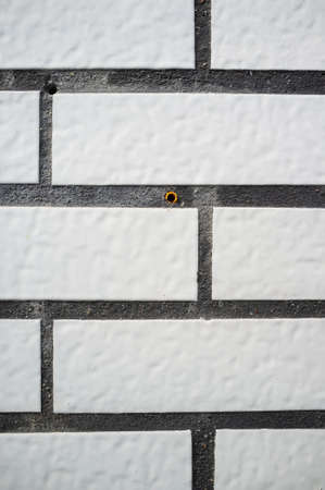 Textured background. Wall of the house is neatly trimmed with tiles that look like white bricks. Copy space.の写真素材