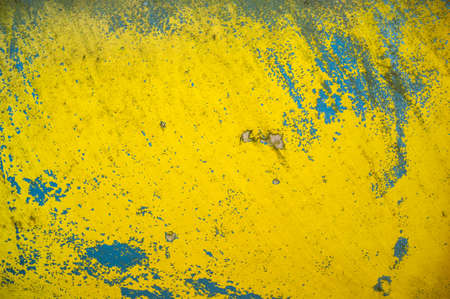 Old wall with scratched peeling blue-yellow paint. Abstract textured background. Copy space.の写真素材