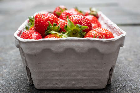 Delicious fragrant strawberries in a paper container, on the table. Red ripe berry is ready to eat.の写真素材
