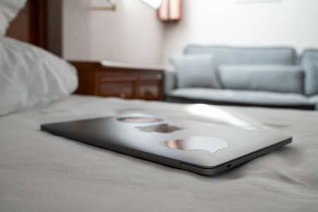 Closed laptop on the bed, in a hotel room. Remote work with ultrabook.の写真素材