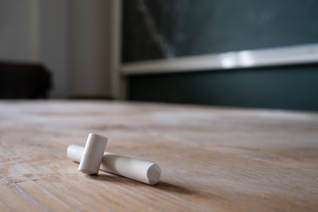 Pieces of white chalk lie on the table, against the background of the blackboard in the classroom. Education concept.の写真素材