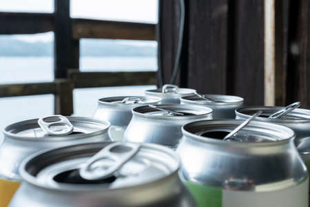 Lot of open aluminum cans, against the background of a window. Empty beer cans. Close-up.
