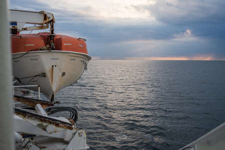Lifeboat hangs on board the ship, against the backdrop of the sea and sky. Beautiful seascape.