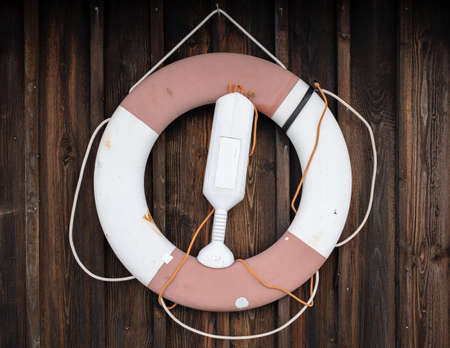 Lifebuoy hangs on the wooden wall of the hut. Safe holiday concept. Close-up.の写真素材