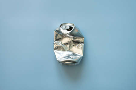 Crumpled aluminum empty soda or beer can, on a blue background. Top view.の写真素材