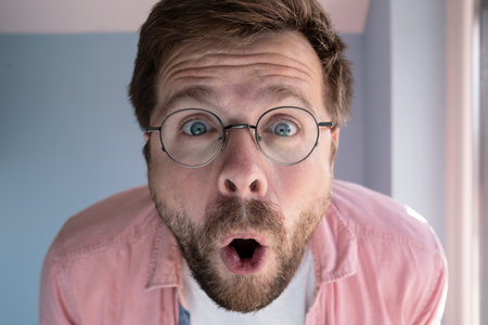 Close-up of an amazed man in glasses, with a funny expression on his face.の写真素材